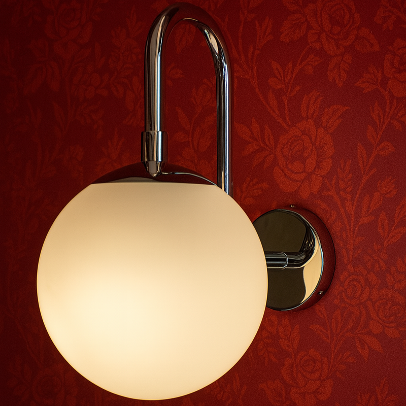 Wall-mounted light fixture with a round glass shade on a red floral-patterned wall.