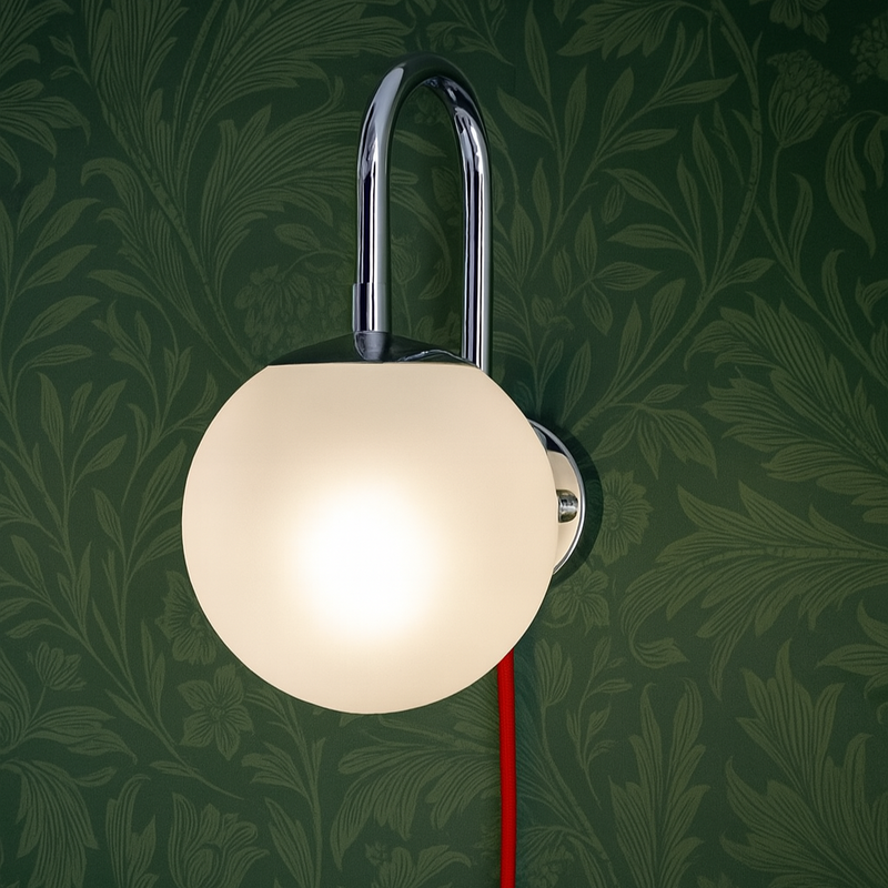 Wall-mounted lamp with a red cord against a dark green leafy patterned background