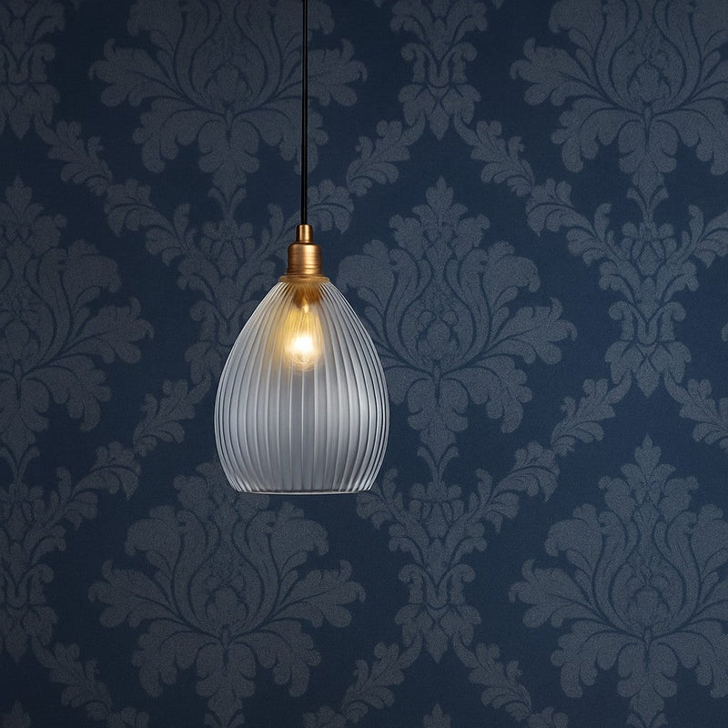 Glass pendant light fixture on a dark blue wall with decorative patterns