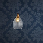 Glass pendant light fixture on a dark blue wall with decorative patterns