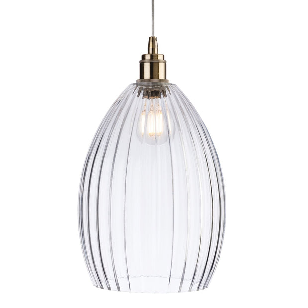 Clear glass pendant light with brass fixture on a white background