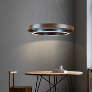 Wooden pendant light hanging above a round wooden table with a chair in a room.