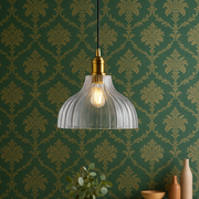 Pendant light hanging above a wooden table with decorative wall paper in the background
