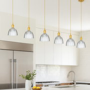 Modern kitchen with pendant lights, white countertops, and wooden stools.