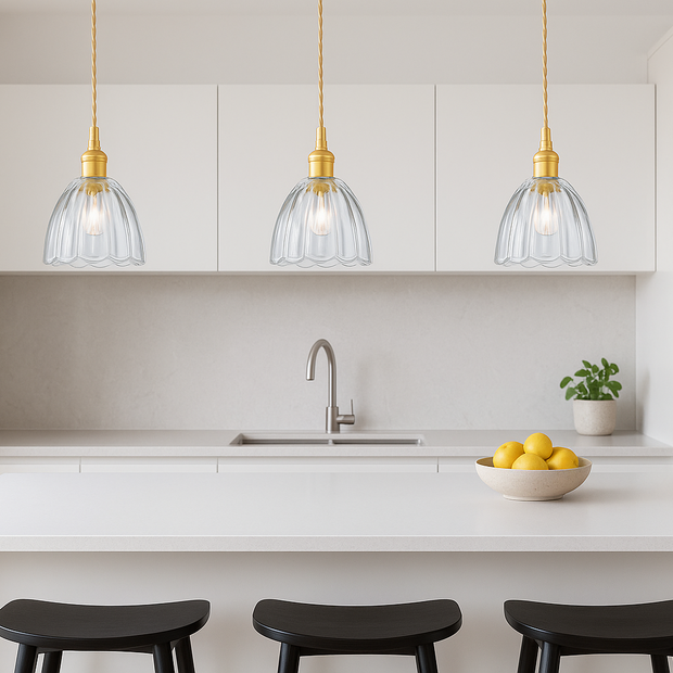 Modern kitchen with white countertops, black stools, and pendant lights.
