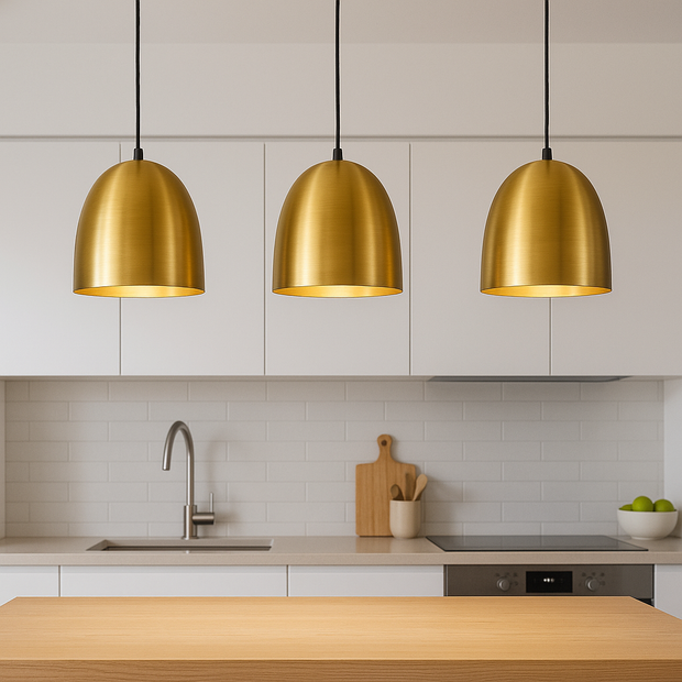 Modern kitchen with gold pendant lights, wooden cutting board, and kitchen utensils.