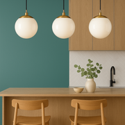 Modern kitchen with wooden counter, stools, and pendant lights against a green wall.