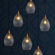 Set of six glass pendant lights with gold fixtures on a dark blue background.