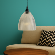 Round wooden coffee table in front of a beige sofa with a zigzag patterned pillow against a teal wall.