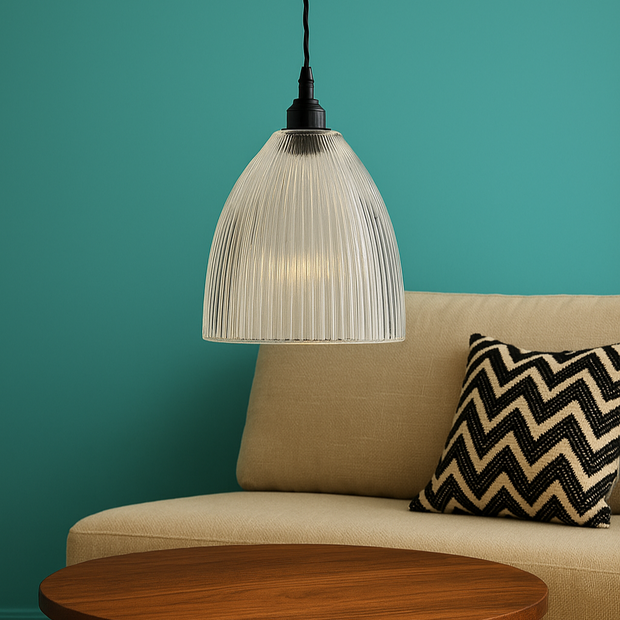 Round wooden coffee table in front of a beige sofa with a zigzag patterned pillow against a teal wall.