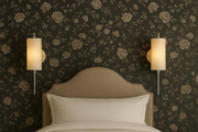Bedroom with floral wallpaper, beige headboard, and wall sconces.